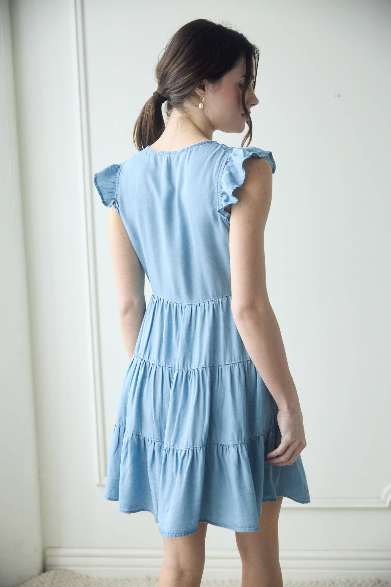 Stylish CHAMBRAY BUTTON DOWN TIERED MINI DRESS with flutter sleeves and a flattering tiered skirt. Perfect for summer!