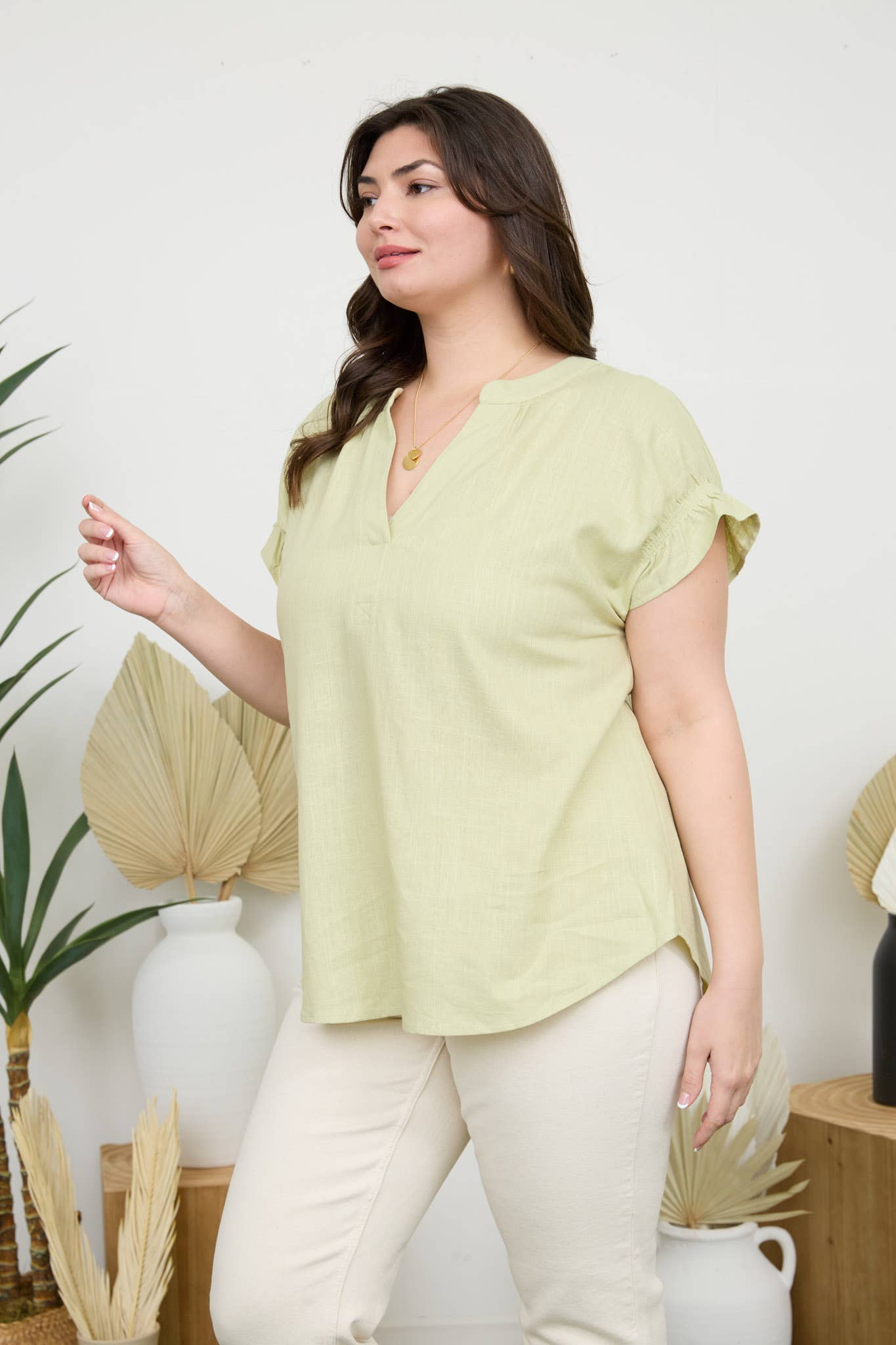 Stylish model wearing a Curvy Ruched Sleeve Linen Blouse in light green, showcasing its relaxed fit and ruched details.