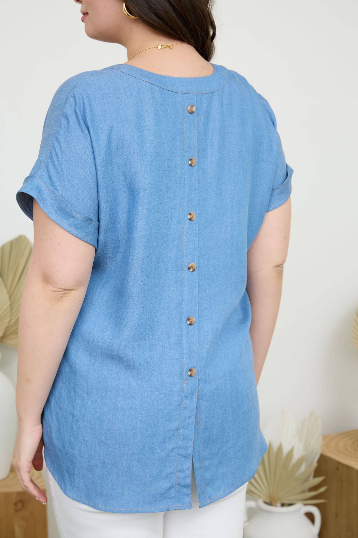 Plus back button cuff sleeve chambray top features a split hem and pocket detail, perfect for a stylish look.