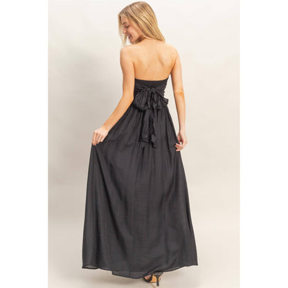 Back view of a strapless tie-back smocked dress in black with a large bow at the back.