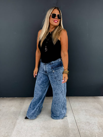 Blonde model wearing Charlie Cinch Hem Wide Leg Jeans in blue denim with black sleeveless top and sunglasses.
