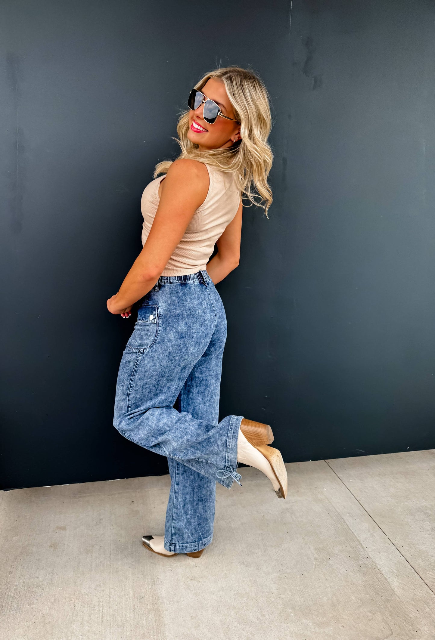 Charlie Cinch Hem wide-leg jeans worn by model Blakeley in beige top, sunglasses, smiling.