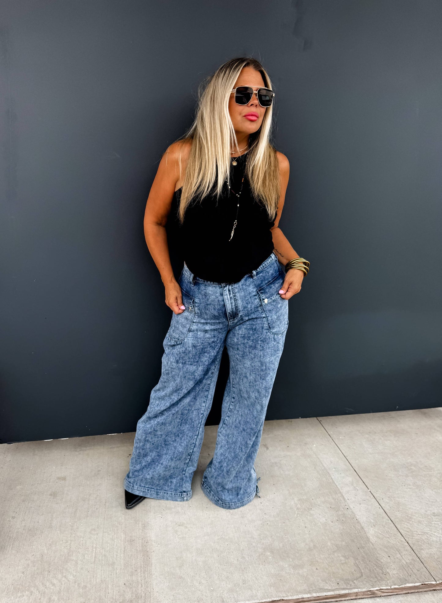 Blonde model wearing light-wash Charlie Cinch Hem Wide Leg Jeans with black top and sunglasses.