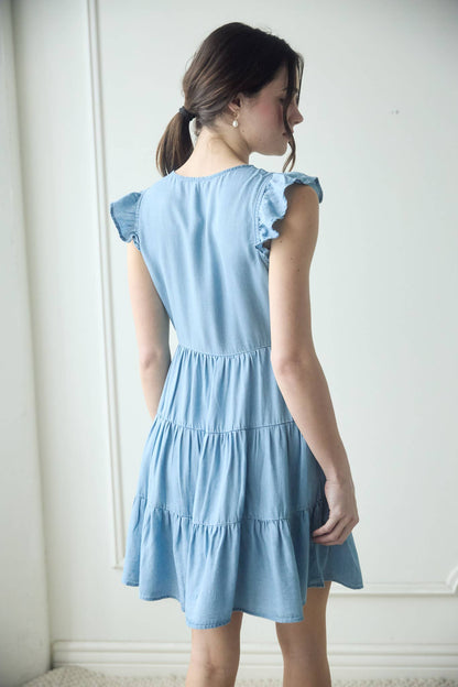 Stylish CHAMBRAY BUTTON DOWN TIERED MINI DRESS with flutter sleeves and a flattering tiered skirt. Perfect for summer!