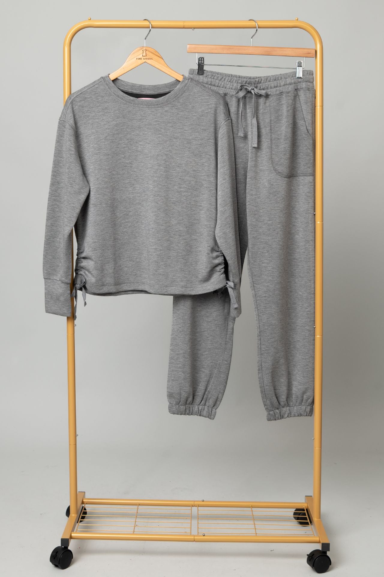 Sport Lux Set gray sweatshirt and jogger pants on a yellow rolling clothing rack.