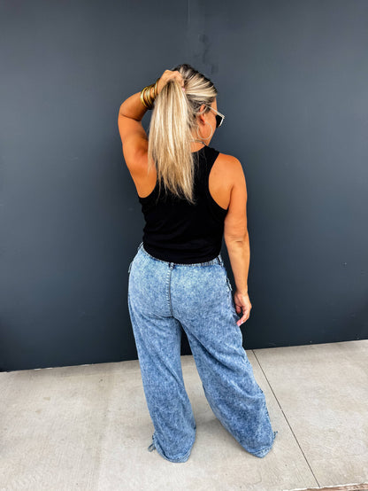 Back view of a woman in Charlie Cinch Hem Wide Leg Jeans with cinched cuffs, elastic waist, light-wash denim.