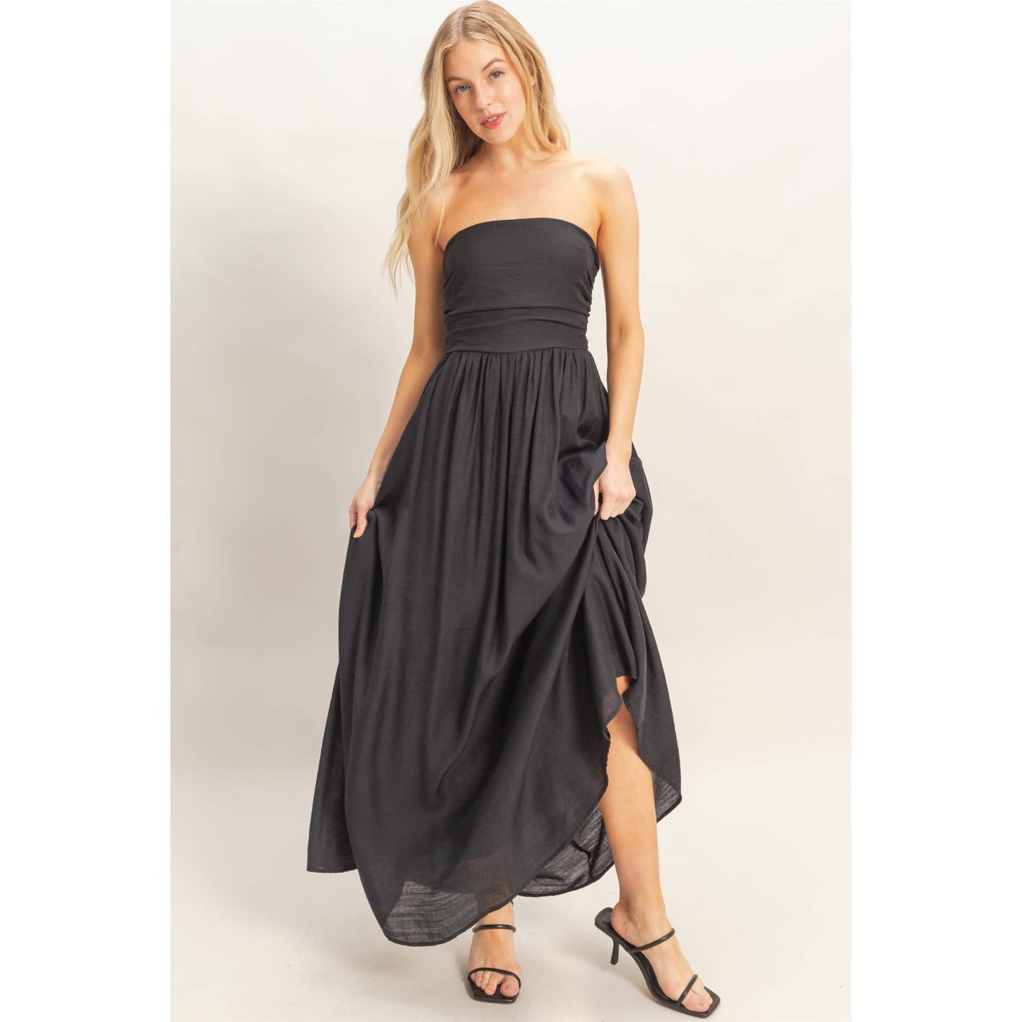Strapless black dress with adjustable smocked back and back tie sash, flowing skirt.