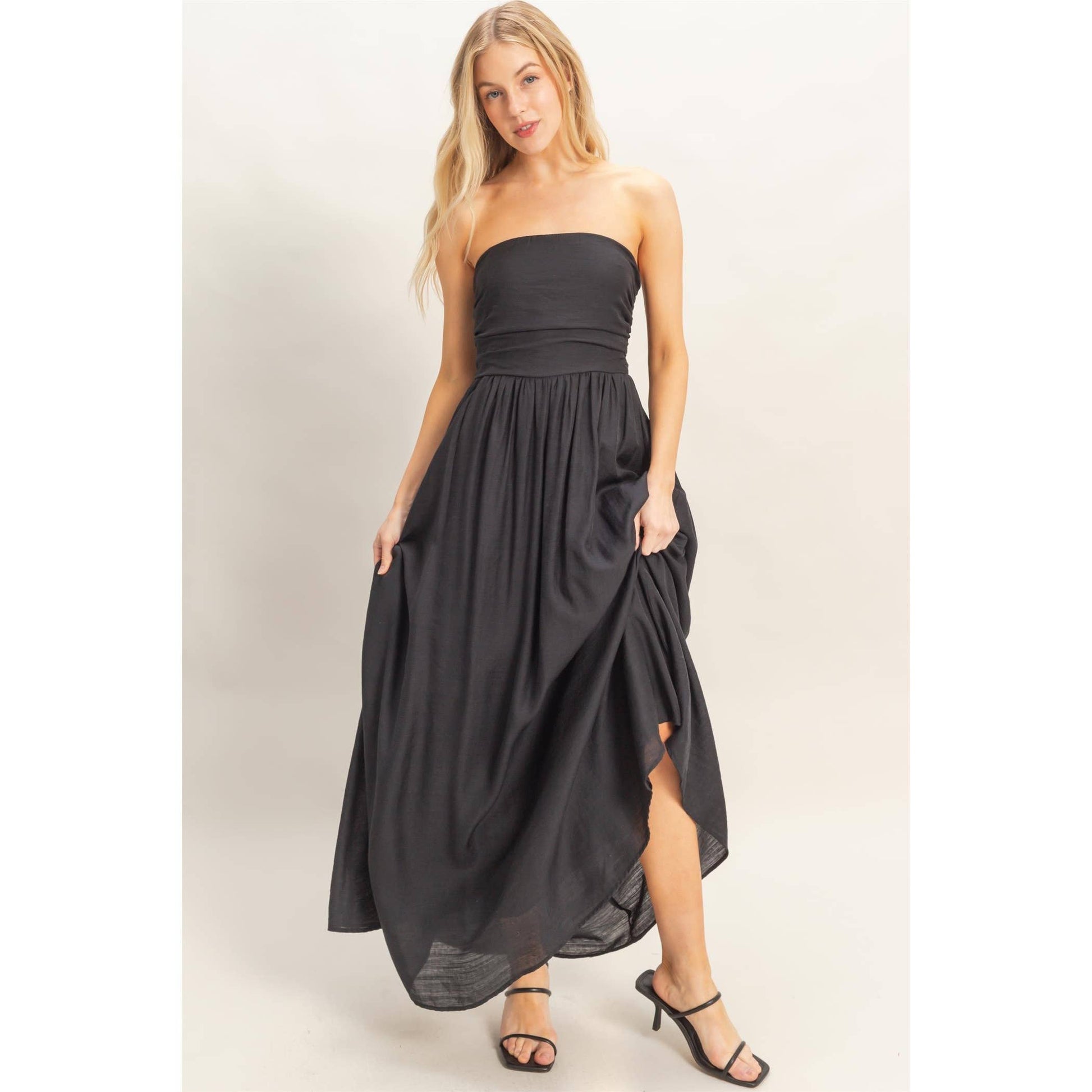 Strapless black dress with adjustable smocked back and back tie sash, flowing skirt.
